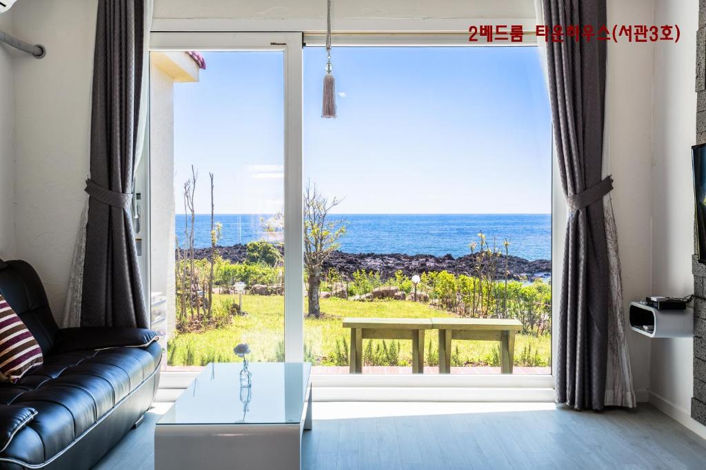 a living room with a view of the ocean at Jeju Turning point Pension in Seogwipo