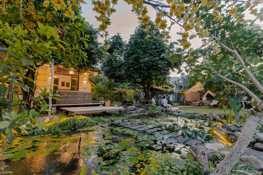 a garden with a pond and a bench and trees at Suoi Da Homestay in Ga Lăng Cô