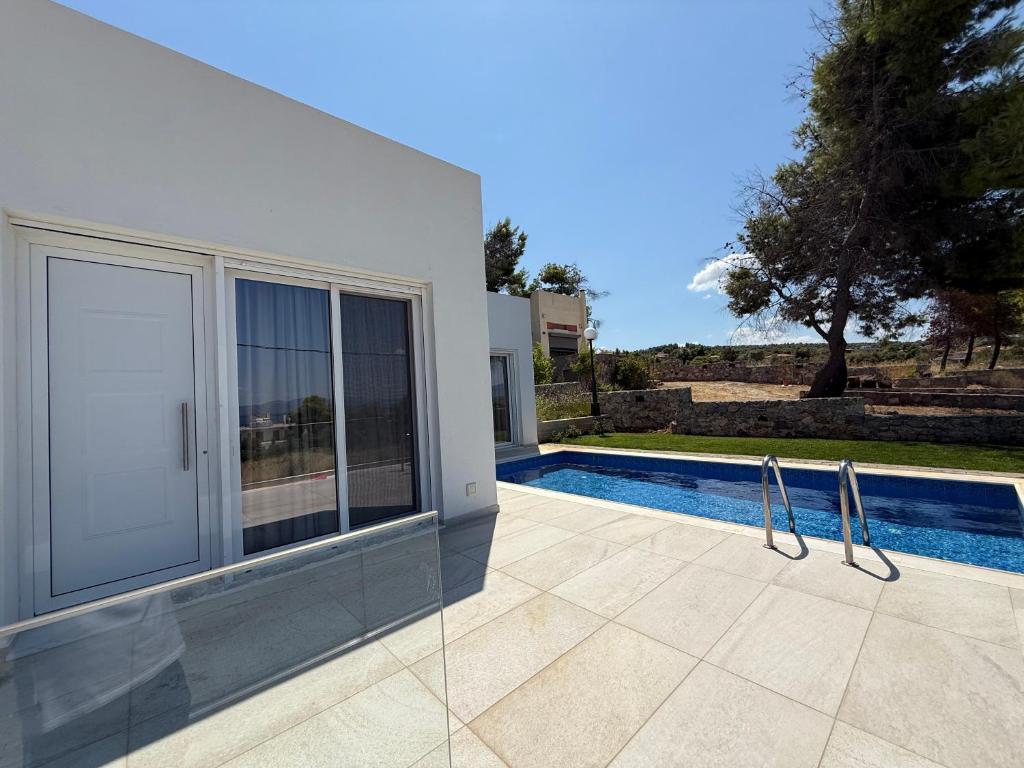 a white house with a swimming pool in front of it at Theologos Residencies in Theologos