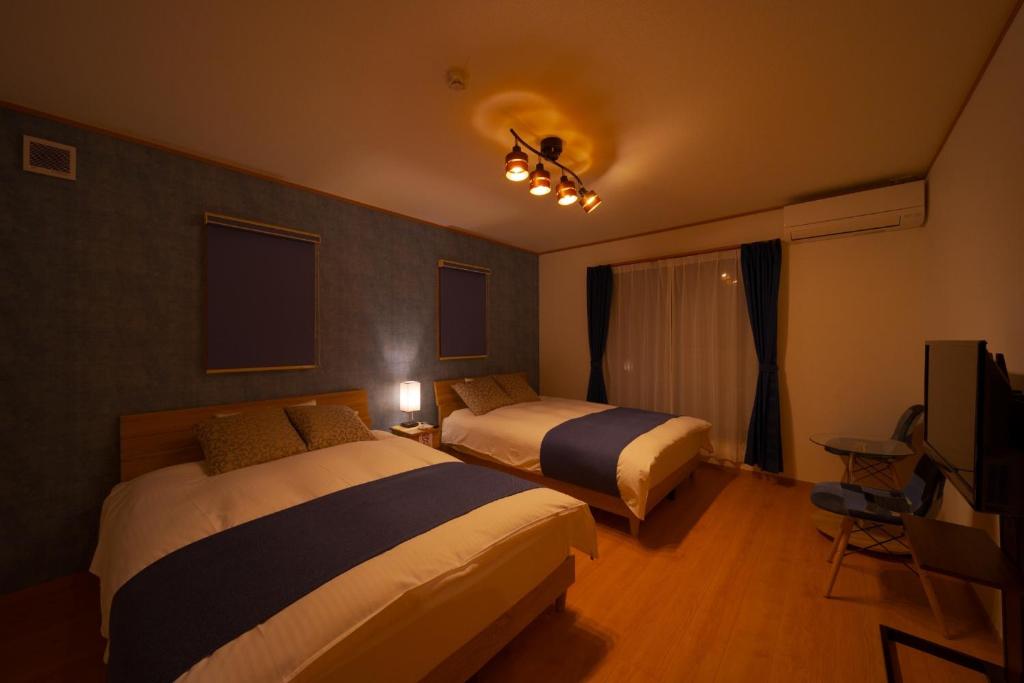 a hotel room with two beds and a television at Takanoya Kumo - Vacation STAY 91939 in Yufuin