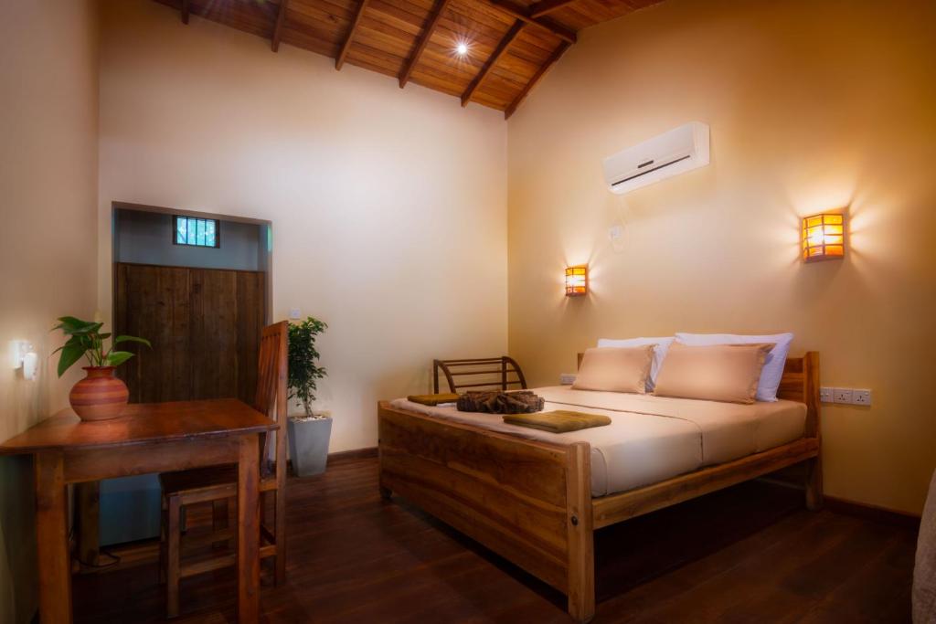 a bedroom with a bed and a desk and a bed sidx sidx sidx at Mora Bay in Arugam Bay