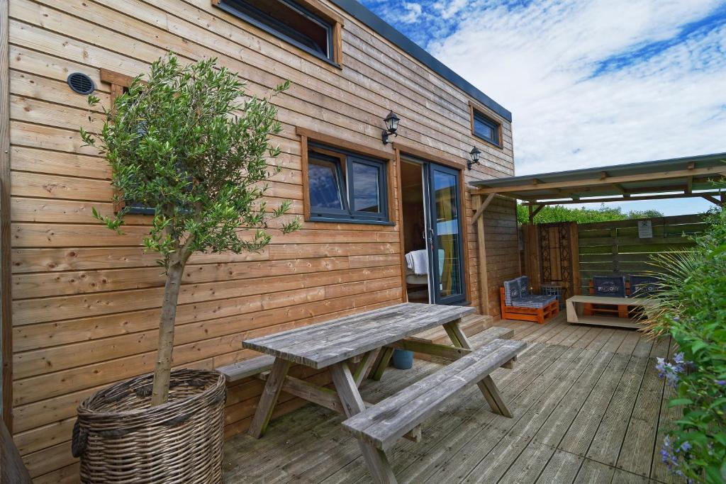 een houten terras met een picknicktafel en een boom bij La Tiny d'Utah Beach - Proche de la plage in Sainte-Marie-du-Mont