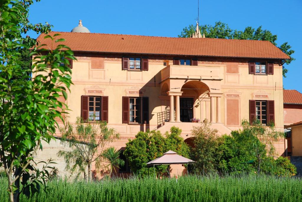 una casa vieja con un campo de hierba delante de ella en Agriturismo Coppi Rossi, en Imperia