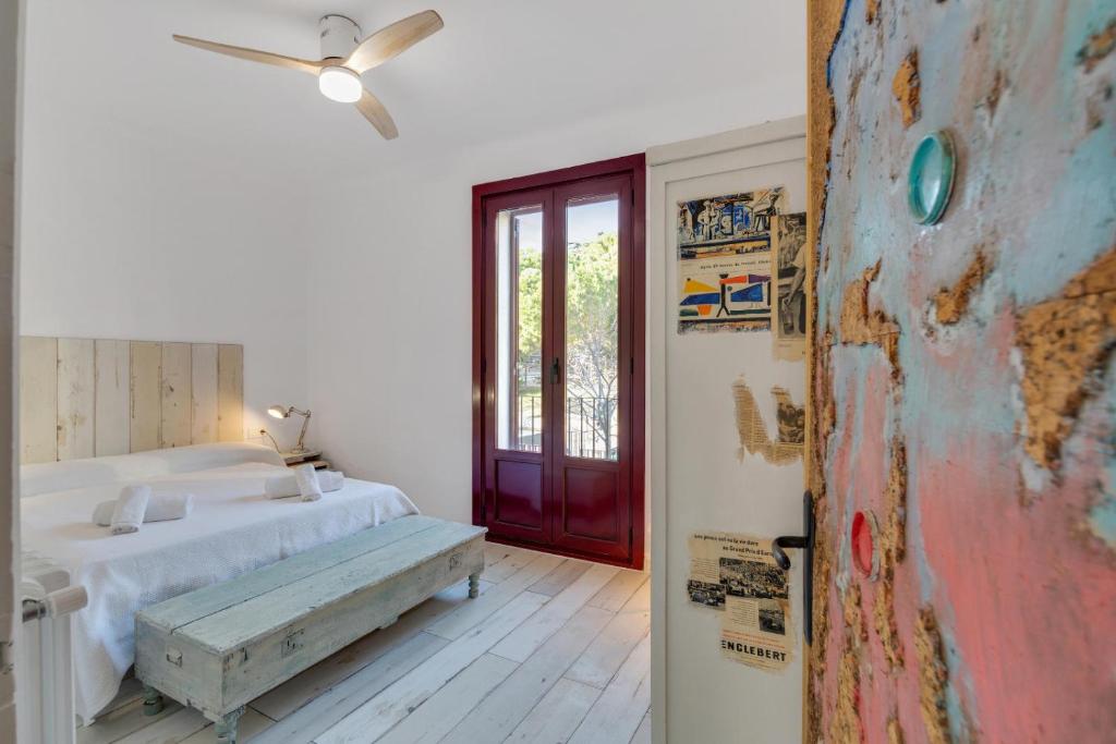 a white bedroom with a bed and a red door at Encantadora casa con terraza y parking en Figueres in Figueres