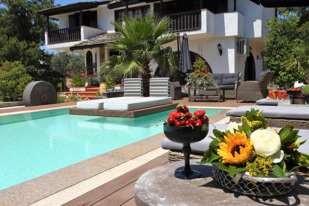 a pool with a bowl of fruit and flowers next to a house at Byblos Luxury Villa in Prinos