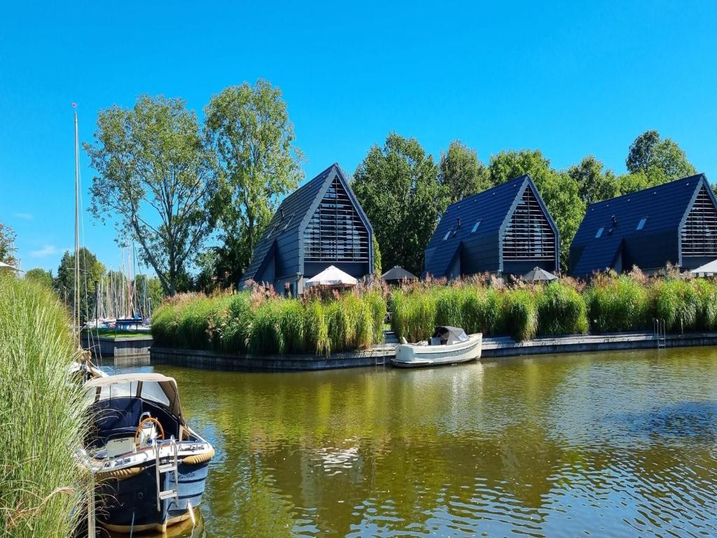 a row of black huts on a river with boats at Luxurious detached water villa with jetty in Balk