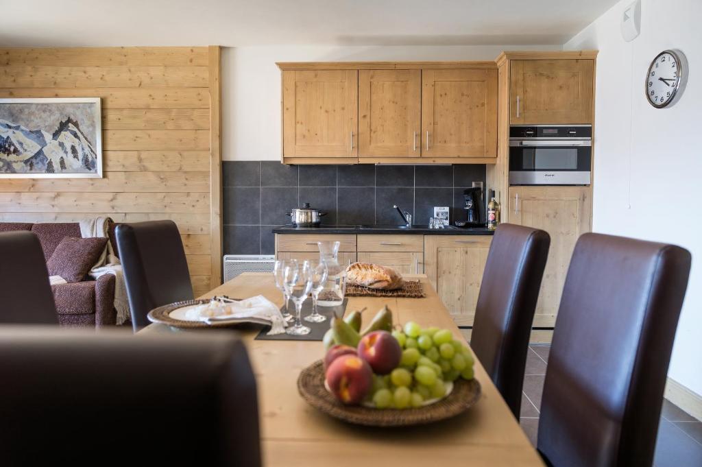 a kitchen with a table with a bowl of fruit on it at CGH Résidences &amp; Spas Chalet Les Marmottons in La Rosière