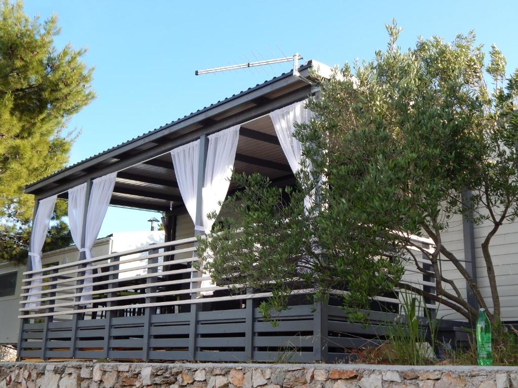 una pérgola con cortinas blancas en una casa en Mobile Home Maslina, en Jezera