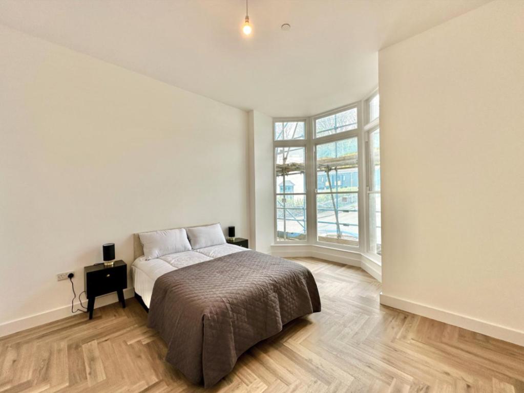 ein weißes Schlafzimmer mit einem Bett und einem Fenster in der Unterkunft Bath House luxury Apartments in Ilfracombe