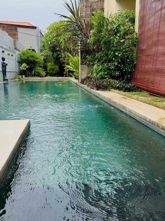 a pool of blue water in front of a building at Perela Homestay Canggu in Canggu