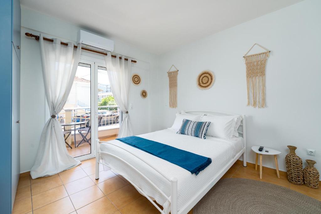 a white bedroom with a bed and a balcony at Eagle's Nest City Apartments in Aígio