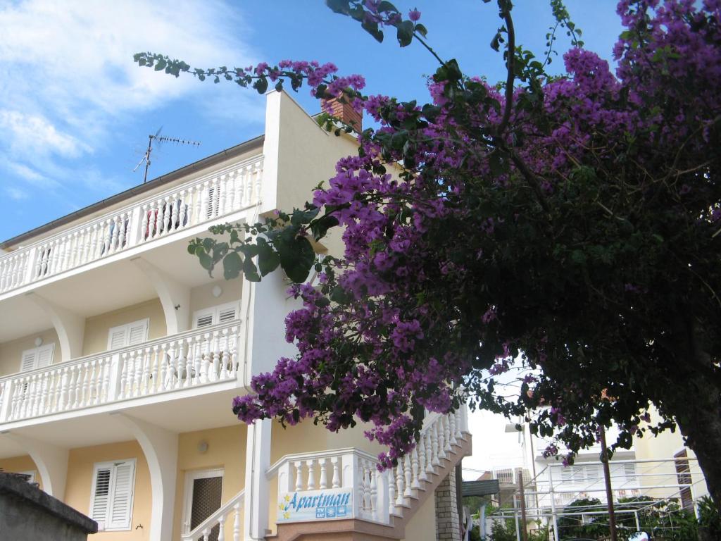 un bâtiment avec des fleurs violettes devant lui dans l'établissement Apartment Nizic, à Primošten