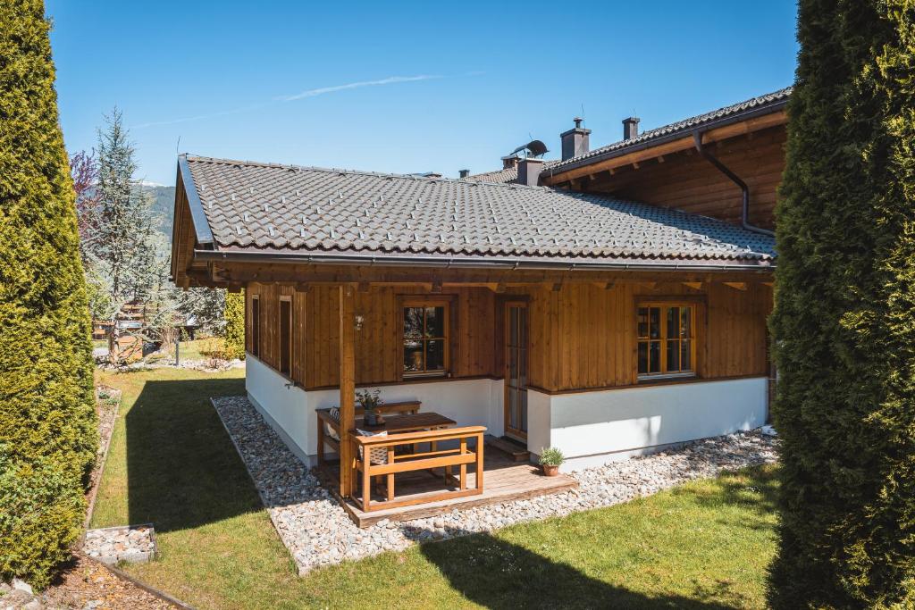 a small wooden house with a bench in a yard at Dorfchalets - Chalet Alma inkl Tauern Spa Therme Eintritt & Sommerkarte in Kaprun