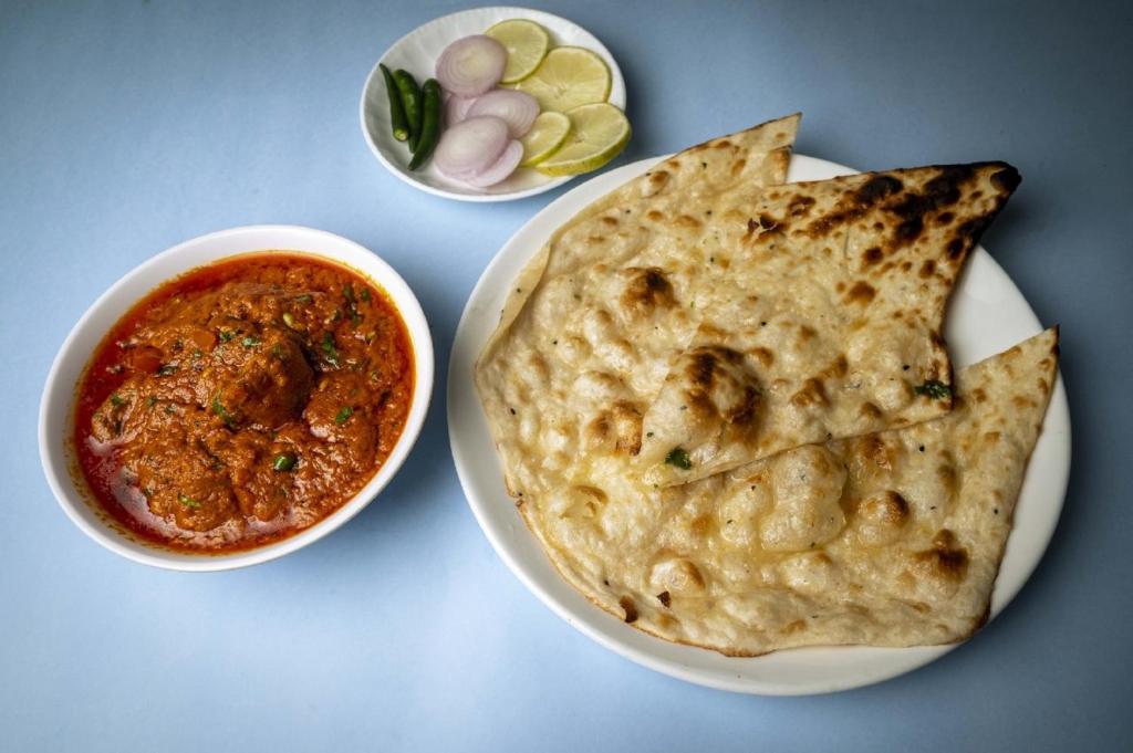 Un plato de comida con un tazón de salsa y un plato de pan pita. en Purple Orchid, en Guwahati