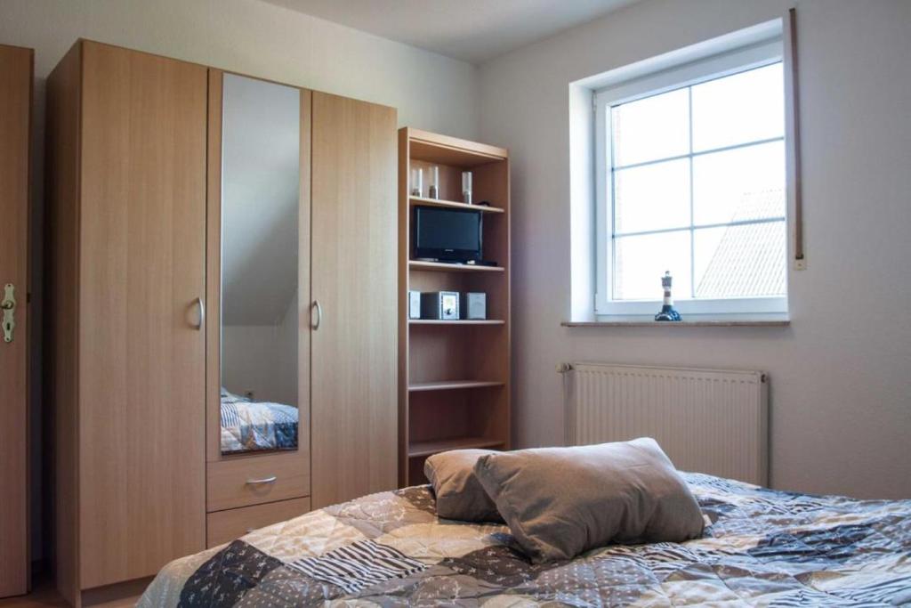 ein Schlafzimmer mit einem Bett, einem Schrank und einem Fenster in der Unterkunft Dat Steenhus - Haustiere Willkommen in Marienhafe