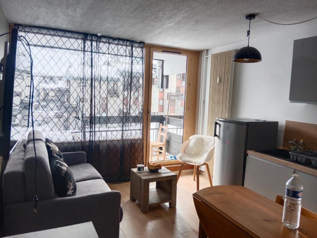 Una sala de estar con un sofá y una cocina. en Studio montagne, en Tignes