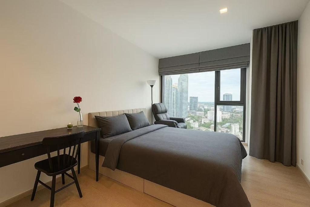 una camera da letto con un letto, una scrivania e una finestra di BTS Thonglor Skyline Condo a Bangkok