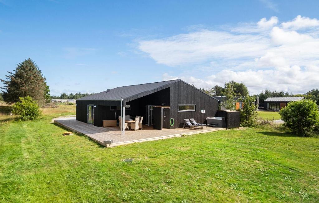 a black building with a deck in a field at Gorgeous Home In Saltum With Wifi in Saltum
