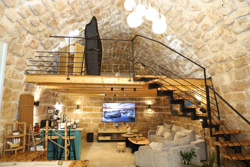 a staircase in a living room with a stone wall at האבן והים - סוויטה מדהימה עם ג'קוזי בעיר העתיקה עכו in Acre
