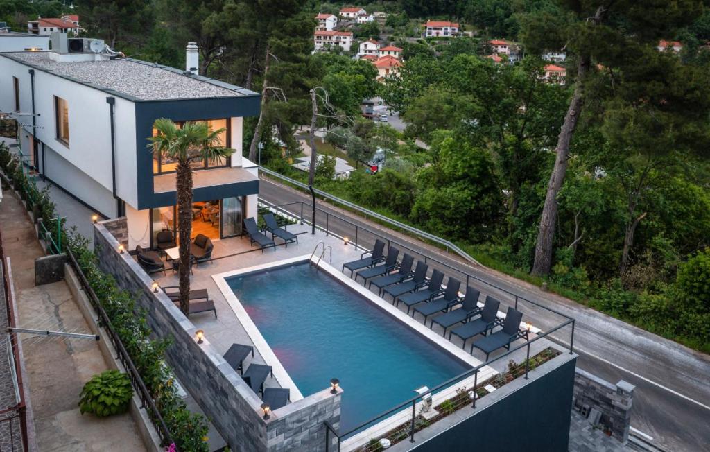 a swimming pool with chairs and a house at Beautiful Villa Magica in Opatija in Mošćenička Draga