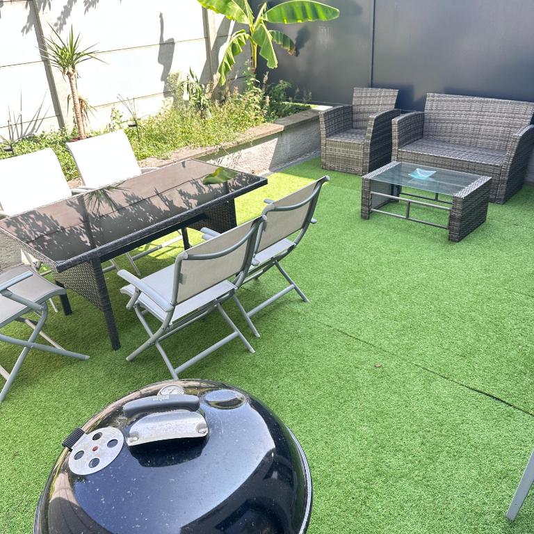 a backyard with a barbecue and chairs and grass at Maison individuelle in Harfleur