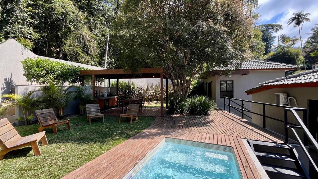 un cortile con piscina e una casa di Casa 23 Floresta Boa Vista - 4 Suítes e Piscina Aquecida em Meio à Natureza a Teresópolis
