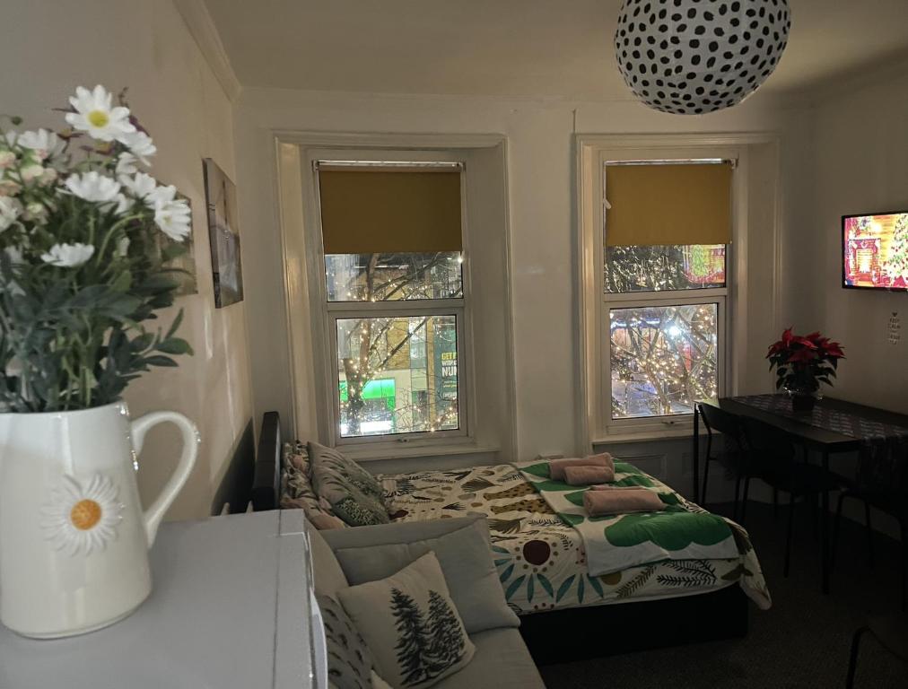 a living room with a bed and two windows at Entire Cosy Flat in Central London in London