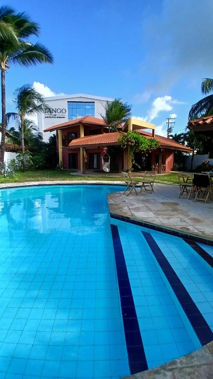 a blue swimming pool in front of a building at Petit Thay Home in Cumbuco