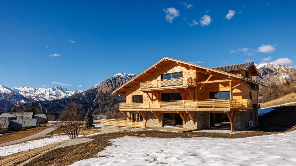 a log home in the snow with mountains in the background at La Licorne de l'Encombrette 150 m2 in Allos