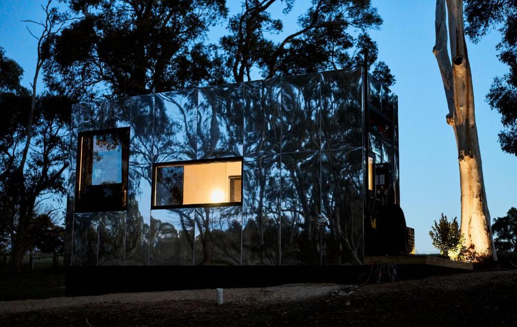 a glass house with two windows in front of trees at Nestled Cabins 