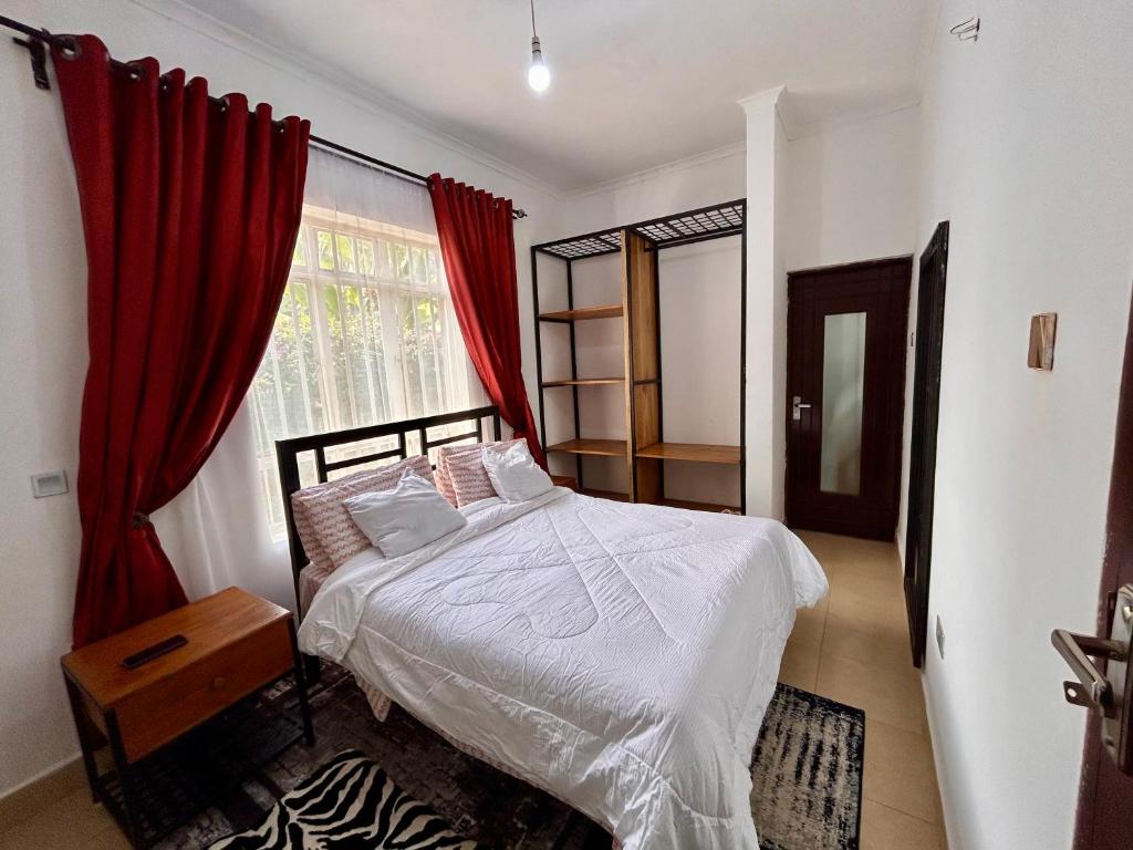 a bedroom with a bed and a window with red curtains at 1 Bedroom- Tranquil Meru Retreat in Nkoanrua