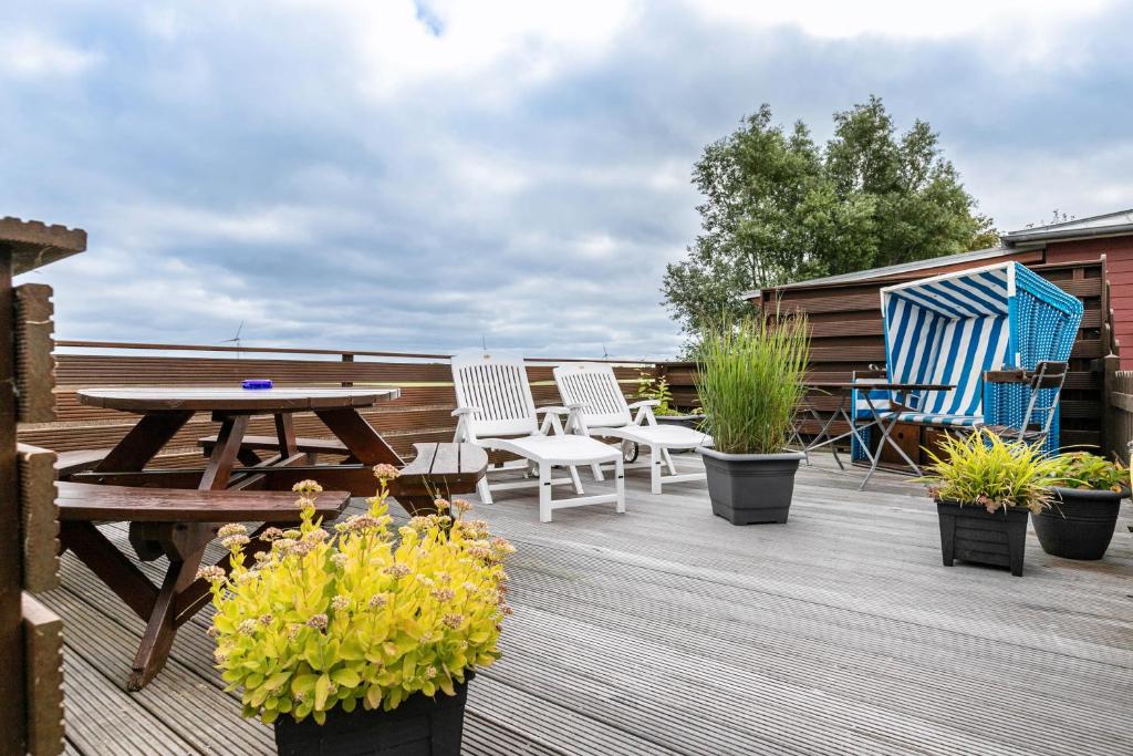 a wooden deck with a picnic table and chairs at Huus achtern Diek - Ferienwohnung 5 in Nordstrand