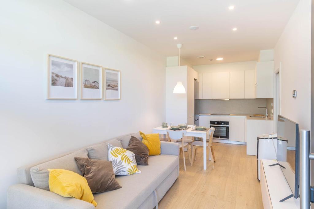 a living room and kitchen with a gray couch and yellow pillows at Acogedor apartamento loft a 15 minutos del centro in Pamplona