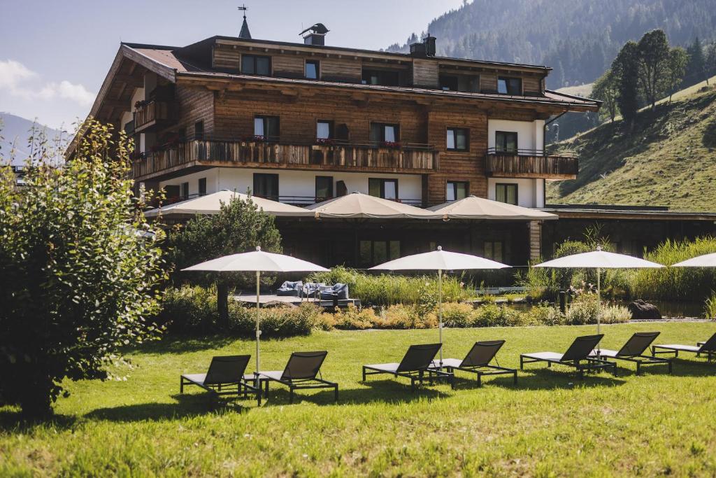 a group of chairs and umbrellas in front of a building at Ski & Bike Hotel Wiesenegg in Saalbach-Hinterglemm