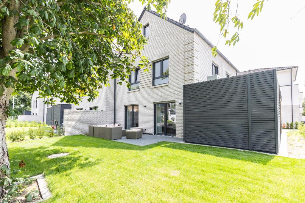 a house with a black fence and a yard at Das Strandhaus 2 in Lembruch