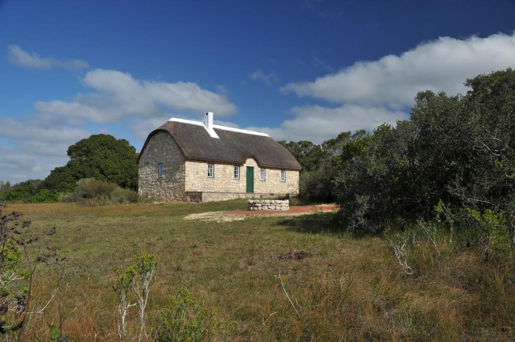 an old stone barn sitting in a field at Melkkamer Foremans Cottage in De Hoop Nature Reserve