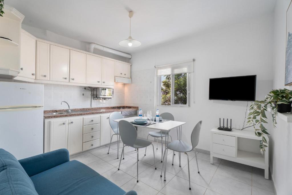 a kitchen with a blue couch and a table and chairs at Apto Beach View Playa los Cristiano in Arona