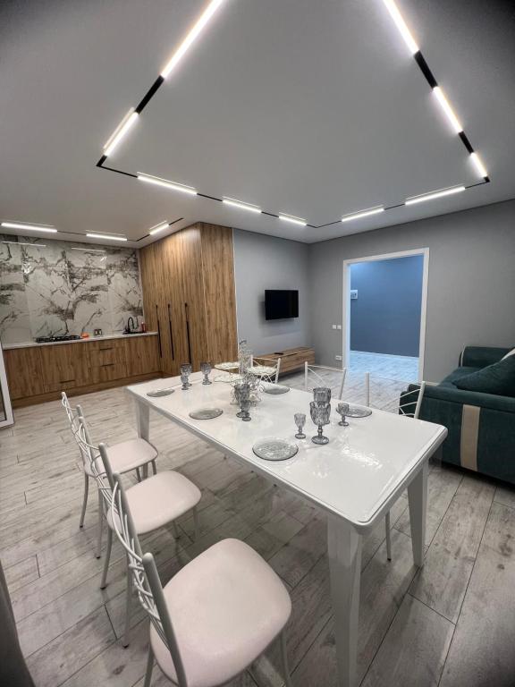 Zimmer mit einem weißen Tisch und Stühlen sowie einem Sofa in der Unterkunft Уютная квартира студия 72 кв in Oral