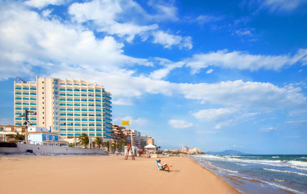 una playa con edificios y gente sentada en la arena en Hotel Servigroup Koral Beach 4 Sup, en Oropesa del Mar