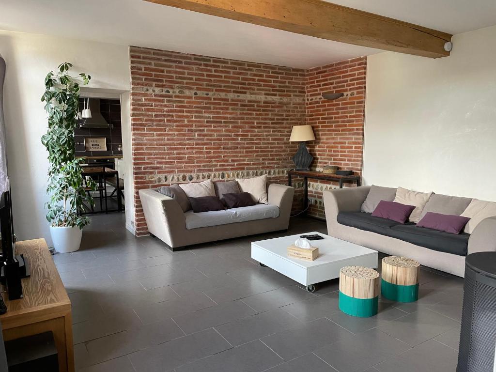 a living room with two couches and a brick wall at Typical Toulouse house completely renovated in Launaguet