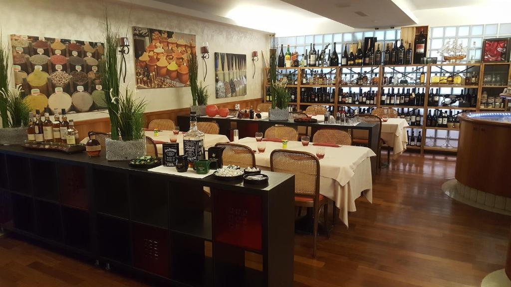 a restaurant with tables and chairs and bottles of wine at Hotel Bahnhof Haus in Chiasso