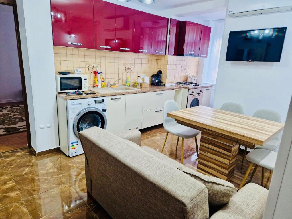 a kitchen with red cabinets and a table and a washer at Cozy apartament Roman in Roman