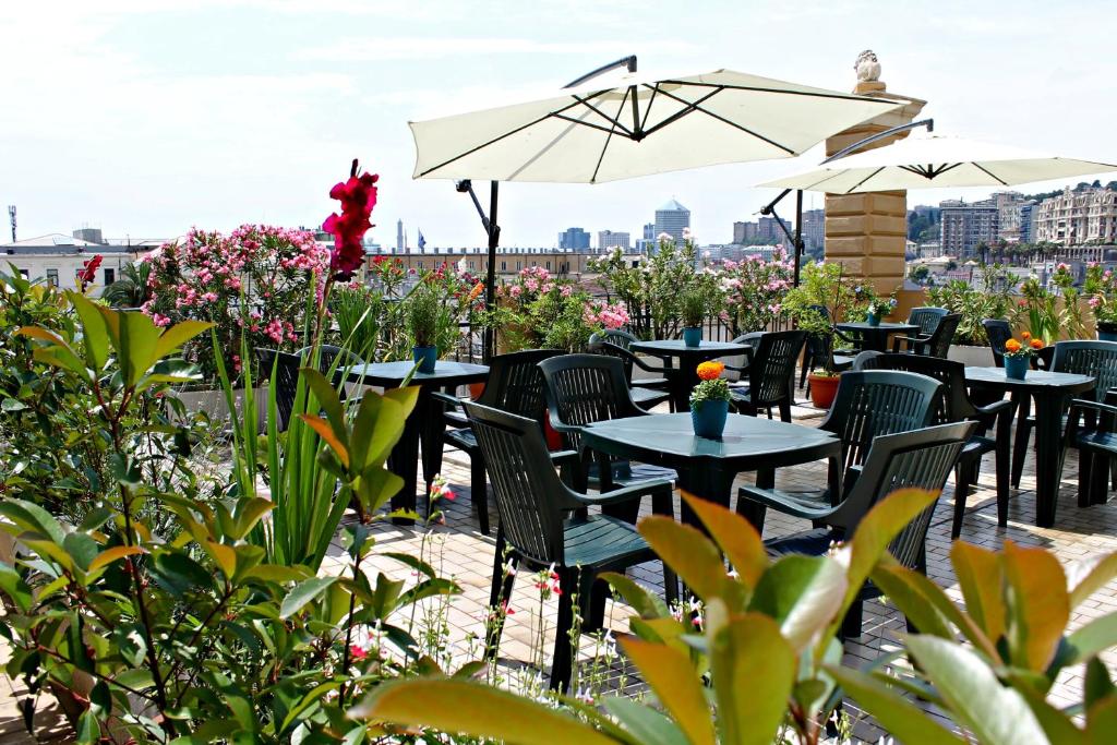 eine Terrasse mit Tischen, Stühlen und Sonnenschirmen in der Unterkunft Hotel Bellevue in Genua