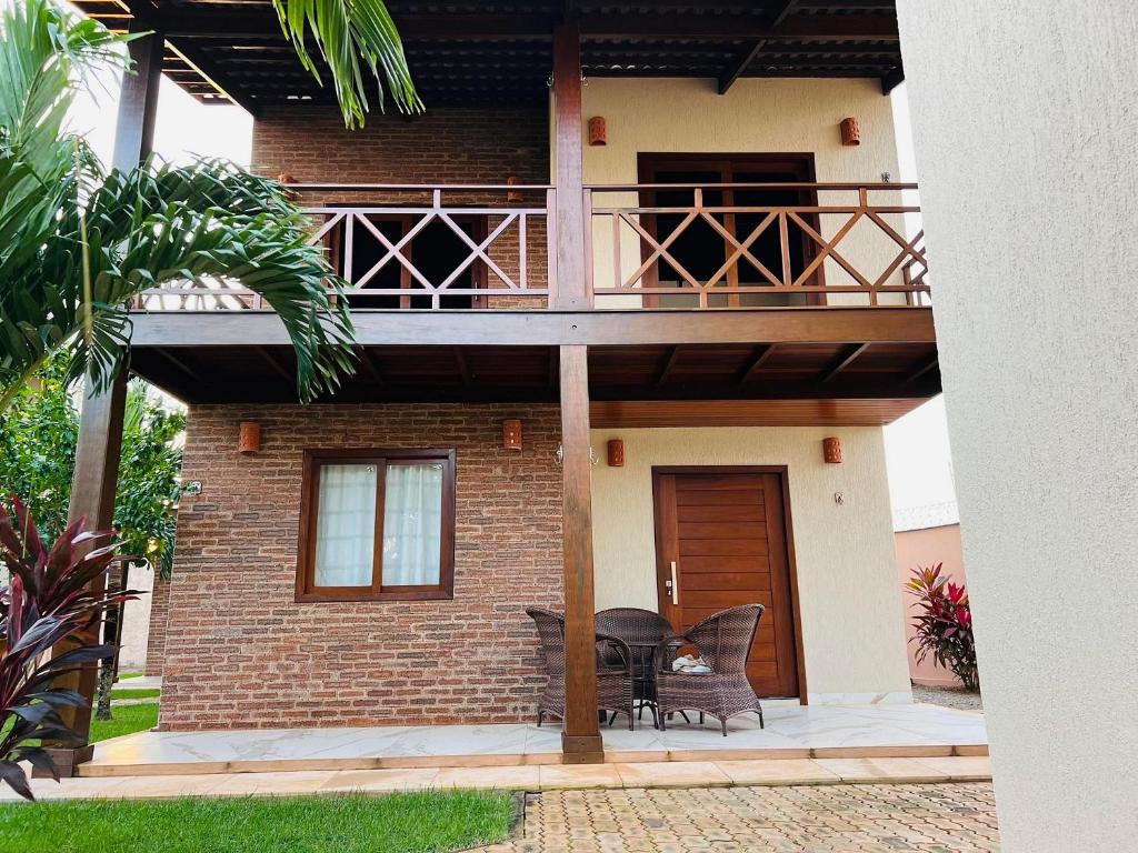 a house with a balcony with a table and chairs at 4let Chalés Sonho de Verão in São Miguel do Gostoso