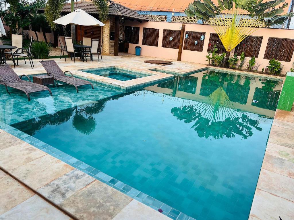 a swimming pool with two chairs and an umbrella at 4let Chalés Sonho de Verão in São Miguel do Gostoso