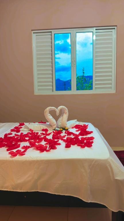 a bed with red roses on top of it at Hospedagem Vô João in Gravatal