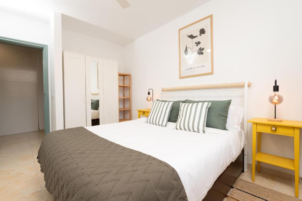 a bedroom with a large white bed and a yellow table at Profithome- Brisas de Güimar in Puertito de Güímar