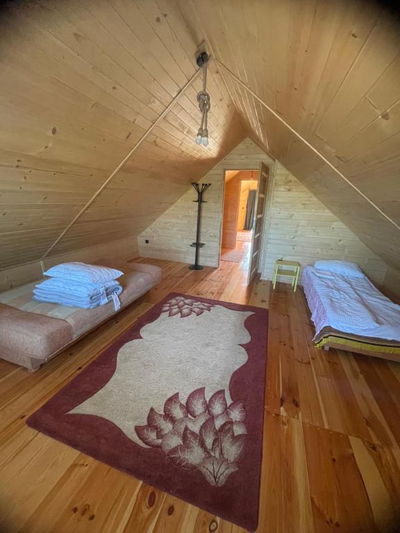 a room with two beds and a rug in a attic at Agroturystyka AKPólko in Biała Podlaska
