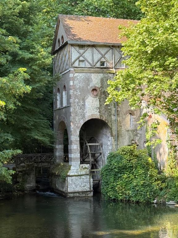 un antiguo edificio con un puente sobre un río en Chambre Solognote, en Saint-Pryvé-Saint-Mesmin
