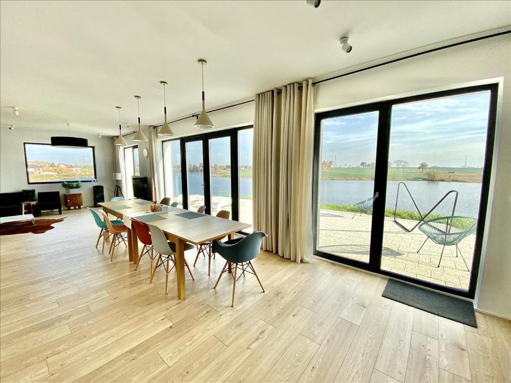 a dining room with a table and chairs and a large window at Lake Beach Villa Mazury in Kałduny